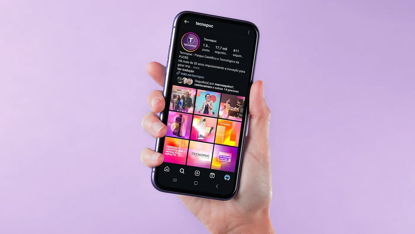 Mão segurando um celular com o perfil do Tecnopuc no Instagram